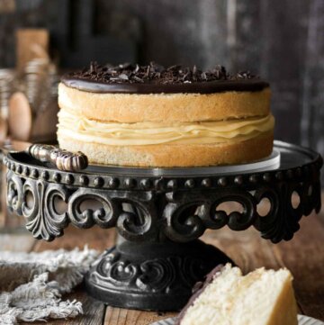 Boston cream pie on a black cake stand, with one slice cut.