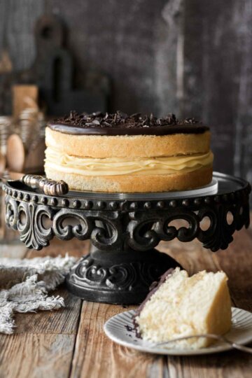 Boston cream pie on a black cake stand, with one slice cut.