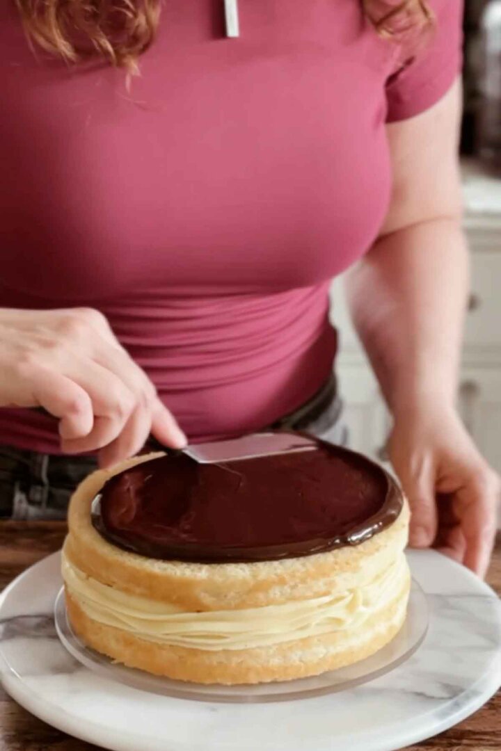 Spreading chocolate ganache on top of a cake.