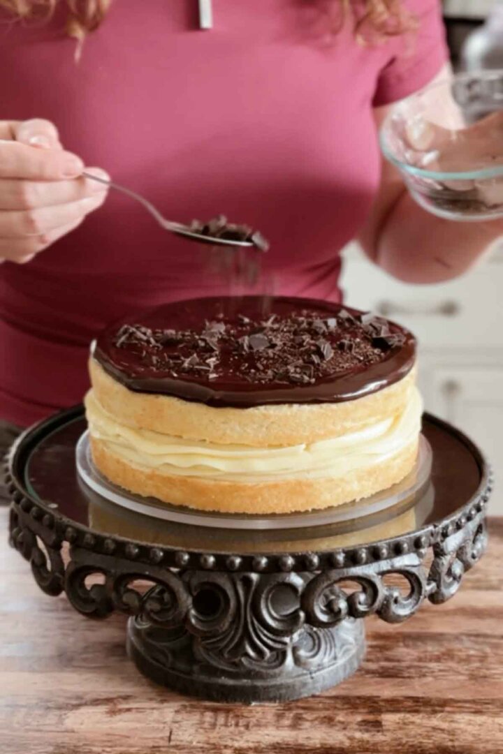 Sprinkling chopped chocolate on top of a cake.
