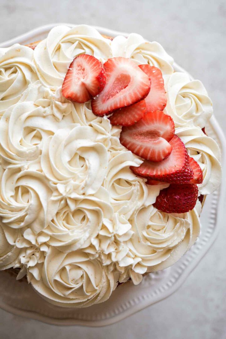 Fresh strawberries and buttercream rosettes on a cake.