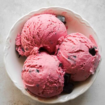 Scoops of homemade raspberry chocolate chunk ice cream in a bowl.