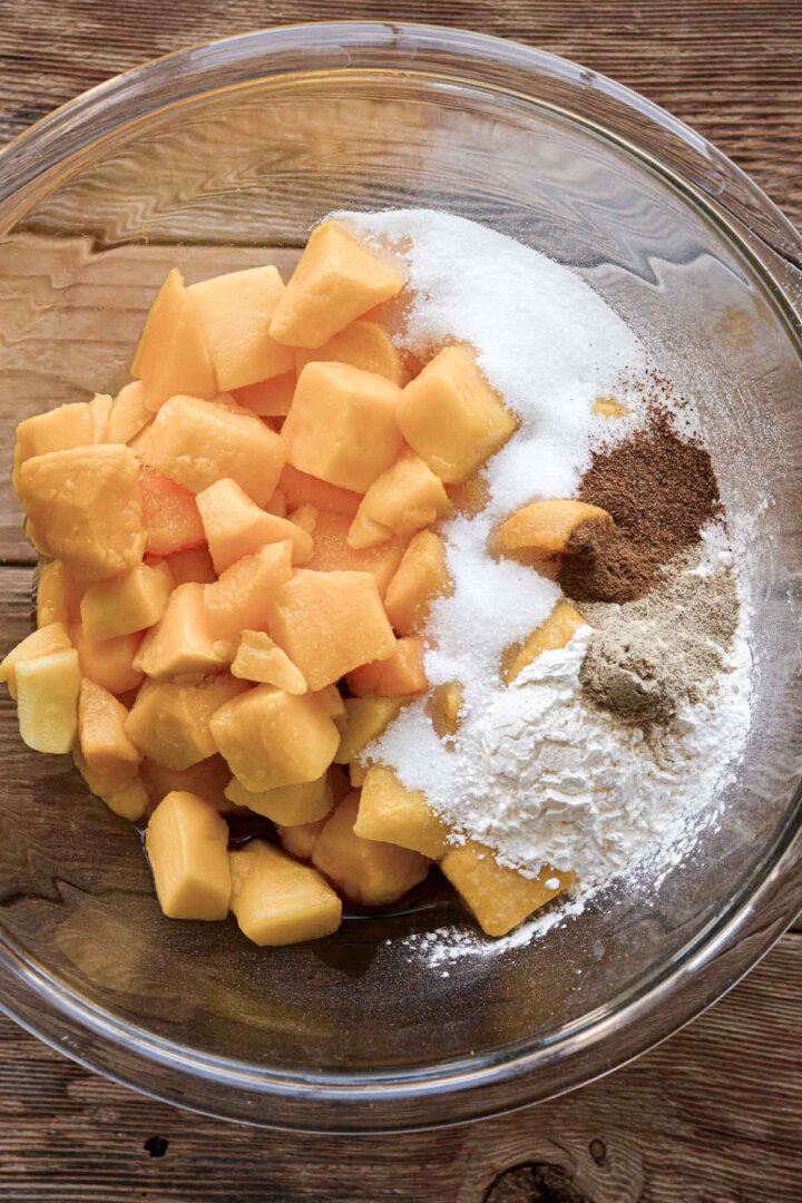 Step 1 for making mango cobbler - mango, sugar and spices in a bowl.