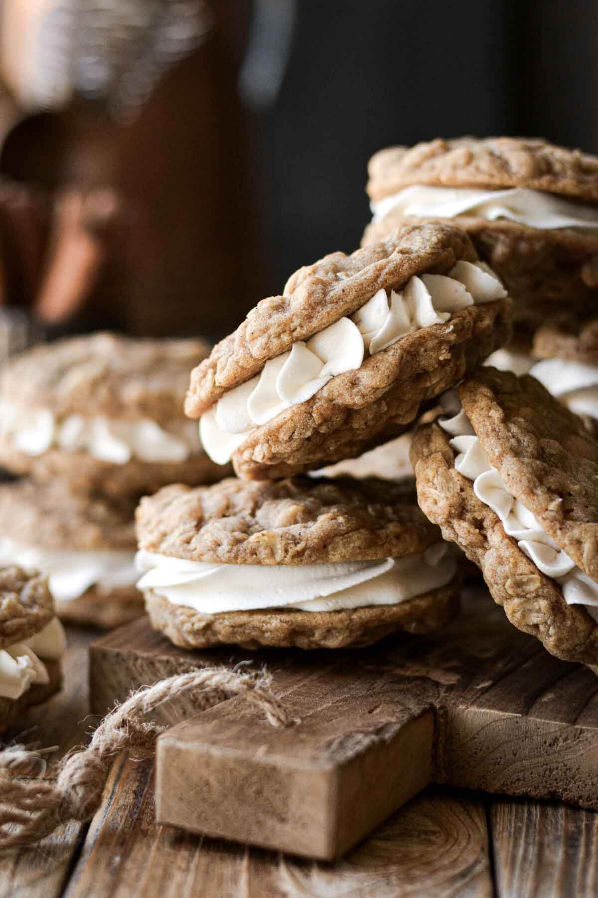 Homemade oatmeal cream pies stacked on a wooden board.