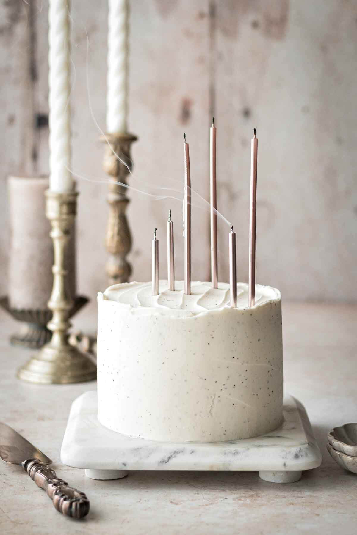 White velvet cake with tall pink birthday candles that were just blown out.
