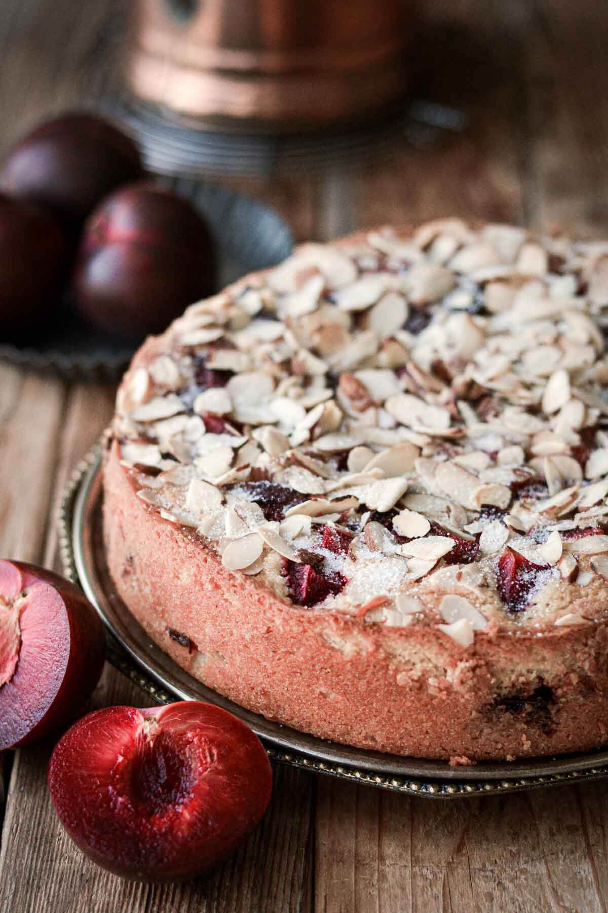 Almond plum cake with sliced plums surrounding it.