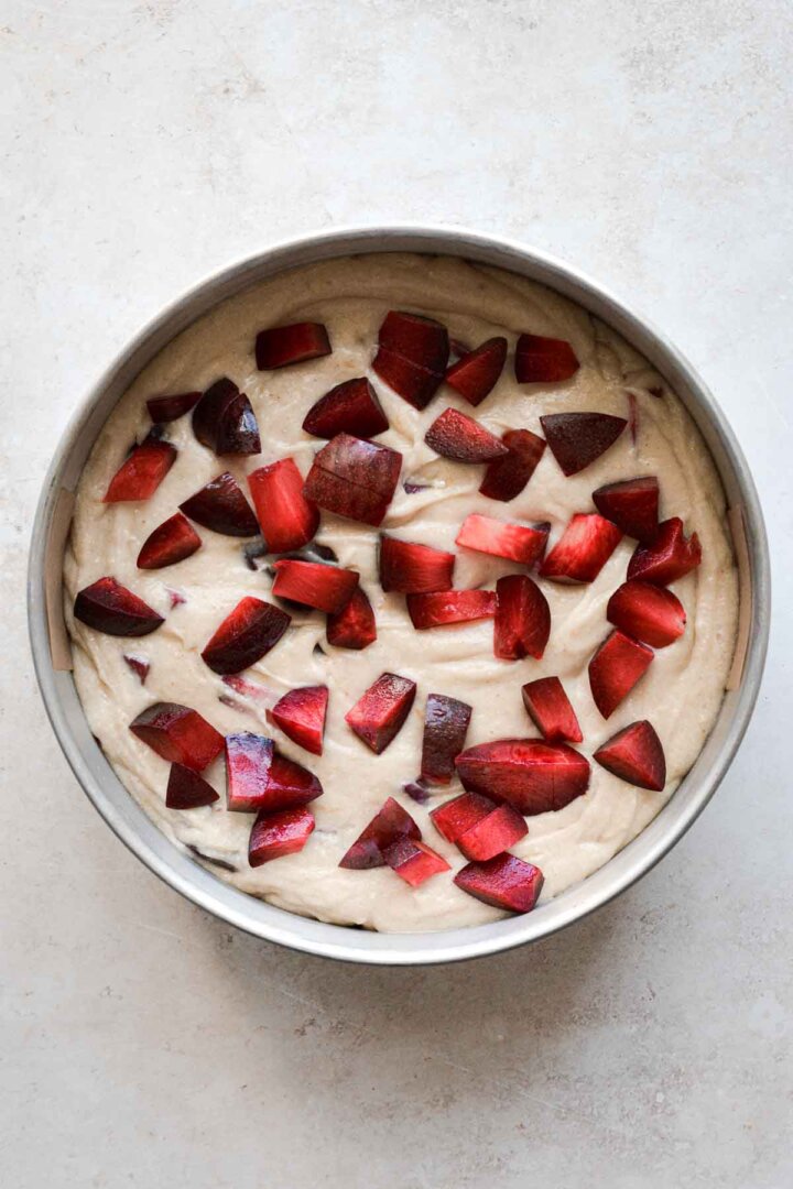 Step 2 for making almond plum cake - chopped plums on batter.