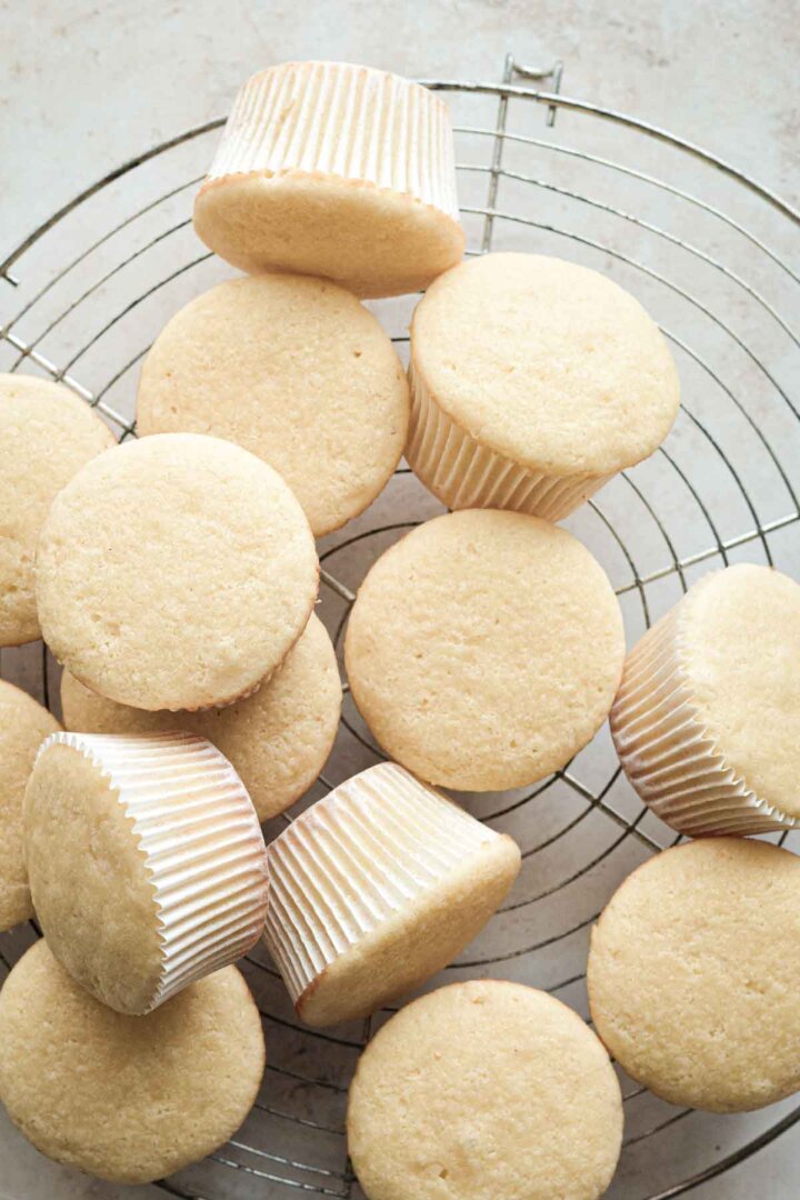 Vanilla cupcakes on a cooling rack.