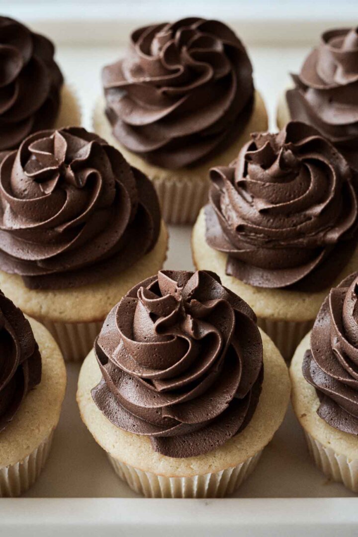Swirls of chocolate buttercream on vanilla cupcakes.