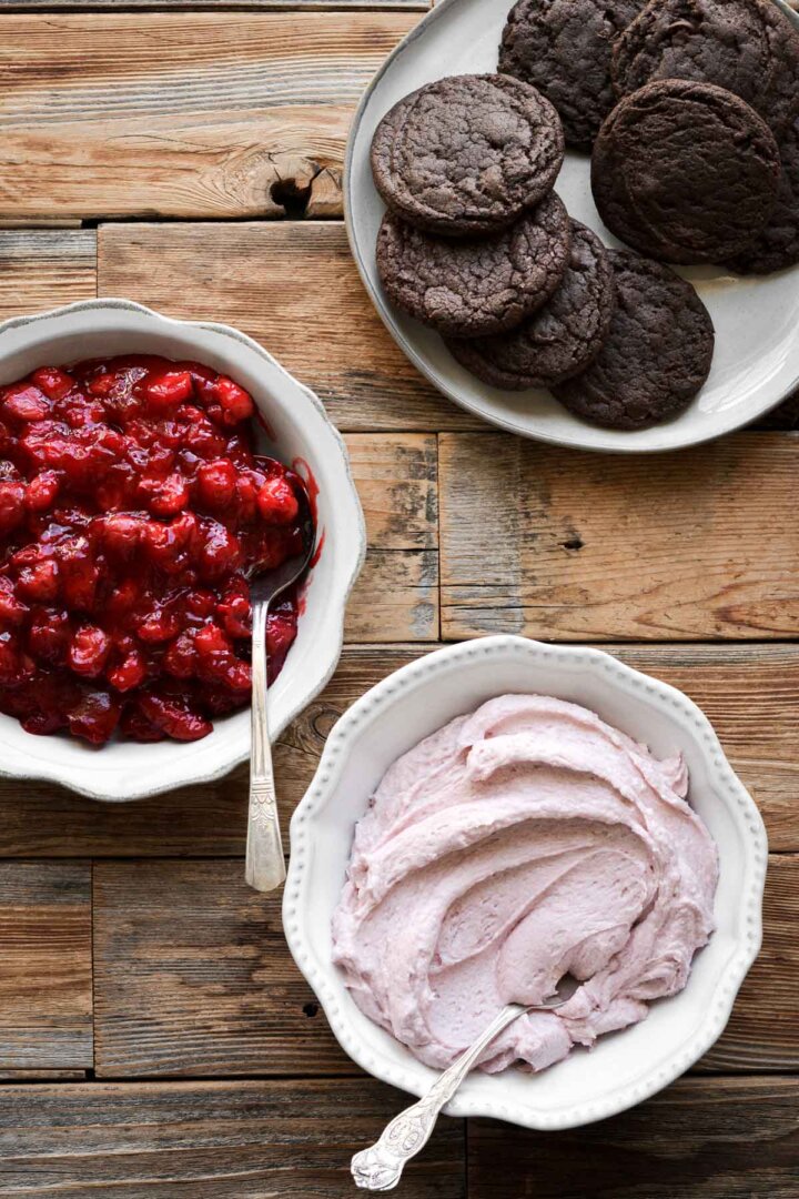 Chocolate brownie cookies, with bowls of cherry pie filling, and pink buttercream.