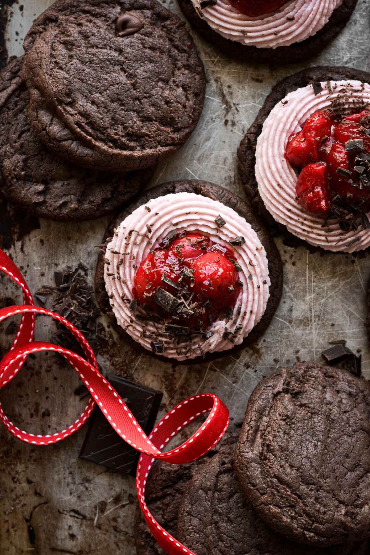Chocolate brownie cookies, topped with pink buttercream and cherry pie filling.