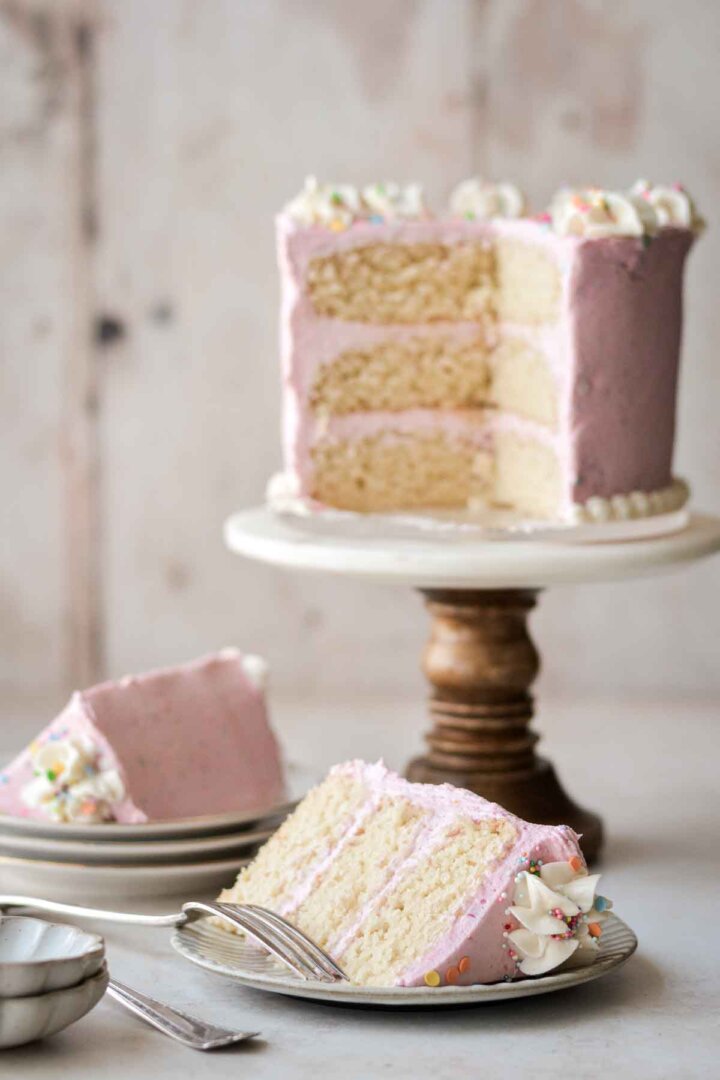 A gluten free vanilla birthday cake with several slices cut.