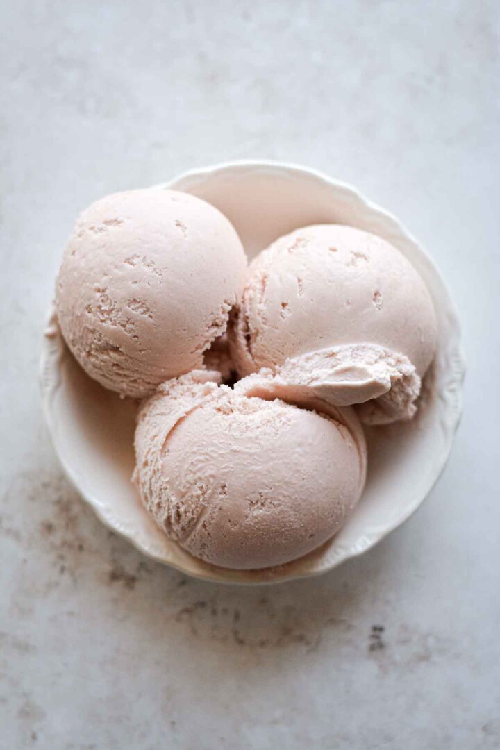 Scoops of rhubarb ice cream in a bowl.