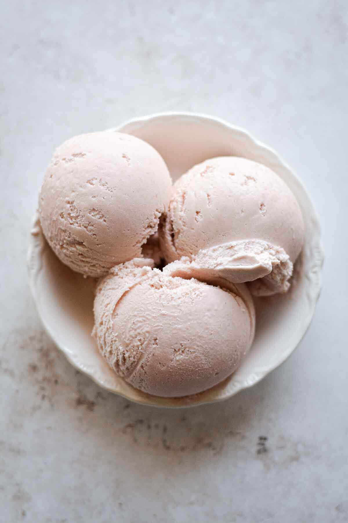 Scoops of rhubarb ice cream in a bowl.