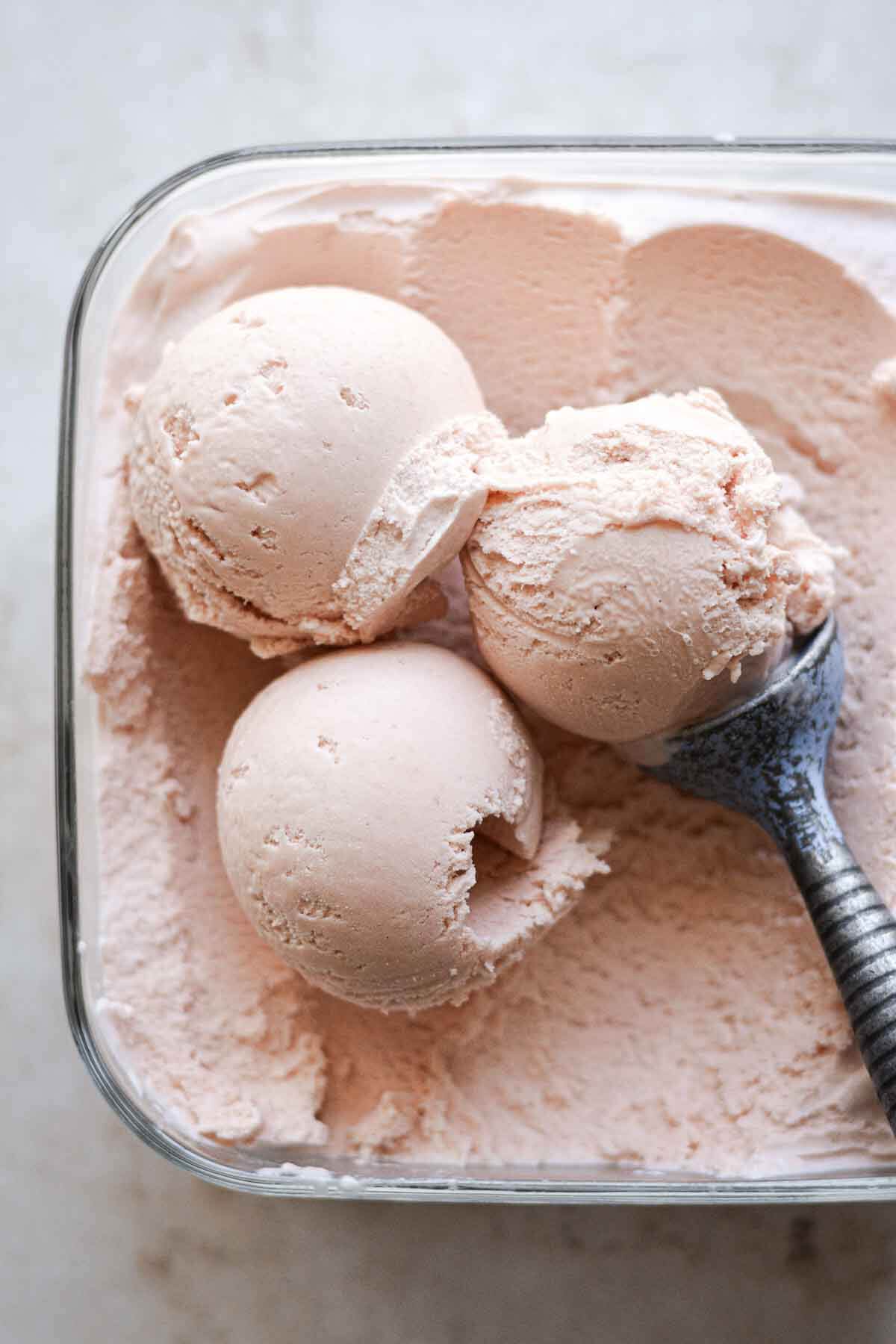 Scoops of rhubarb ice cream with a blue vintage scooper.