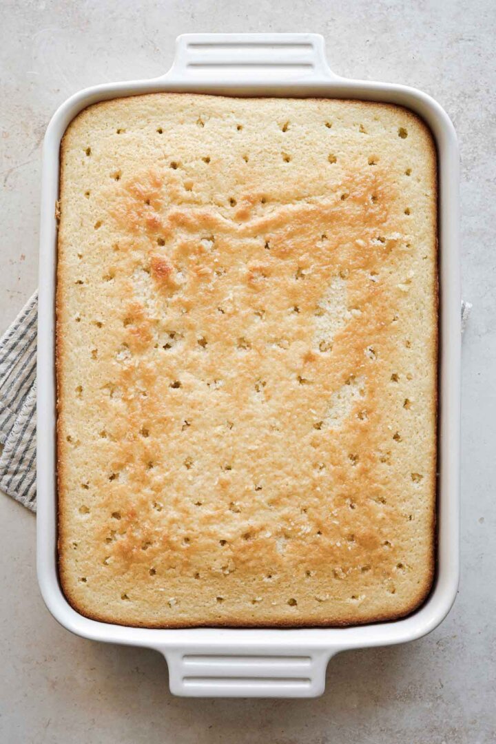 Vanilla sheet cake with holes poked in it.