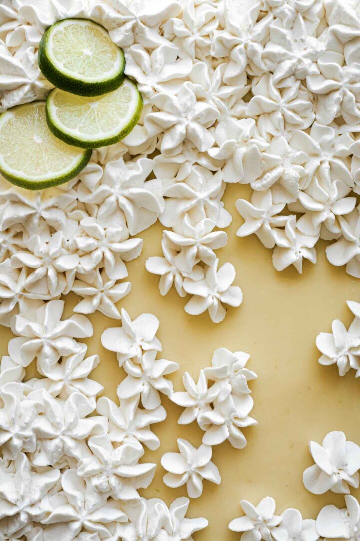 Whipped cream piped in little flowers onto a cake.
