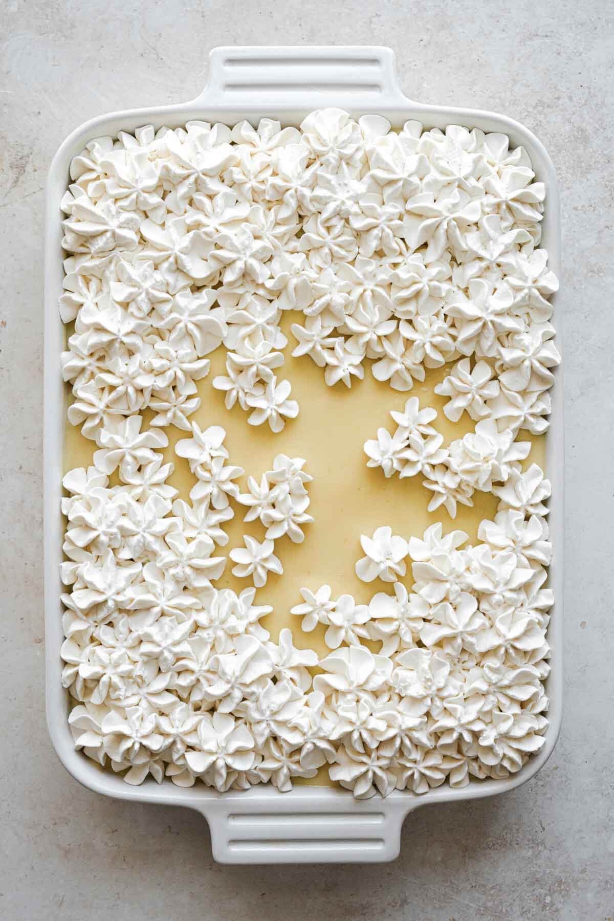 Key lime pie sheet cake with whipped cream flowers on top.
