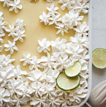 Key lime pie sheet cake with whipped cream flowers and lime slices on top.