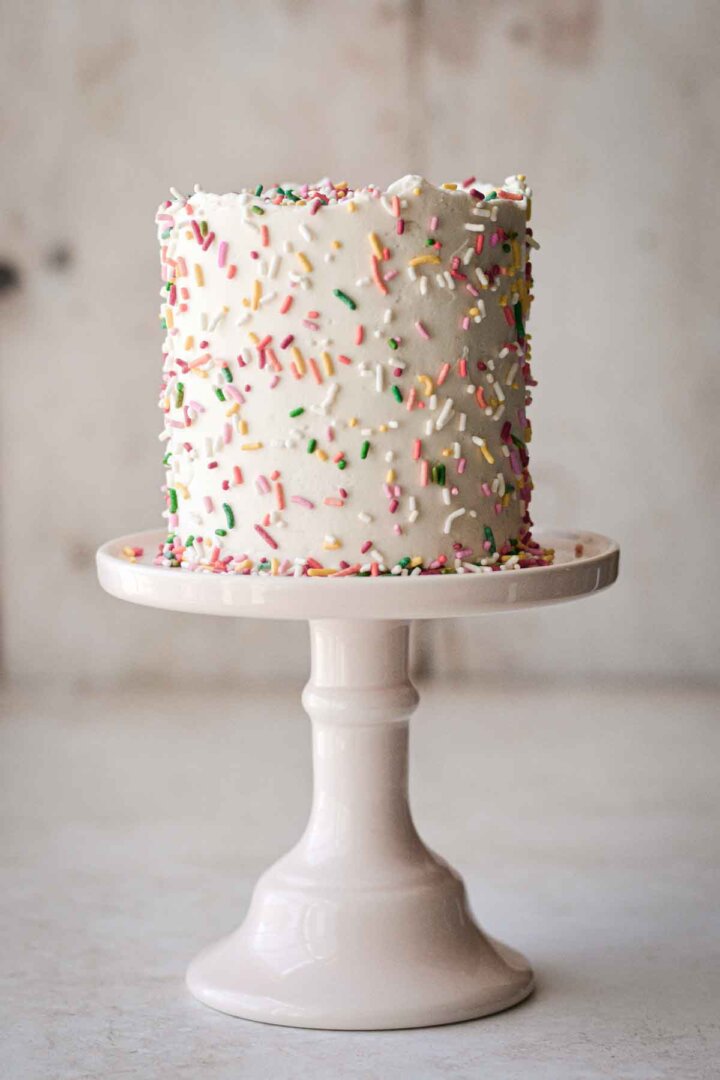 Mini confetti cake with sprinkles, on a pink cake stand.
