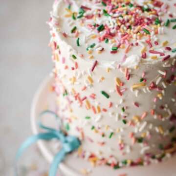 Mini confetti cake, covered with sprinkles, decorated with a blue ribbon.