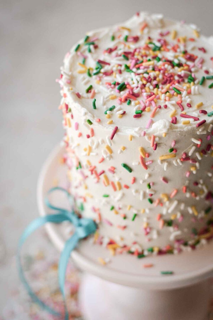 Mini confetti cake, covered with sprinkles, decorated with a blue ribbon.