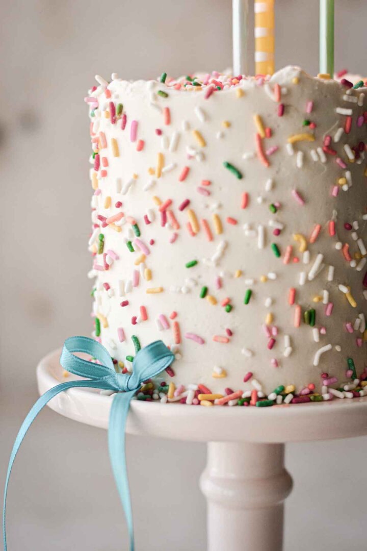 Mini sprinkle cake with a blue ribbon on it.