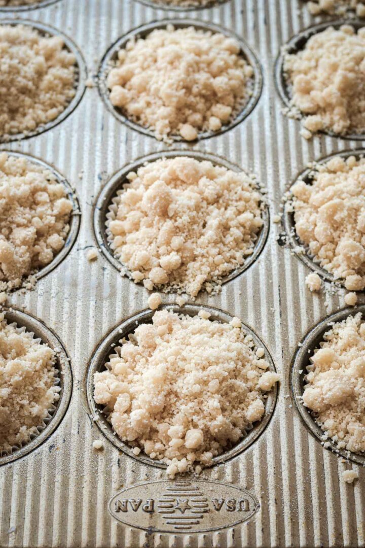 Step 5 for making almond poppy seed muffins - crumb topping sprinkled over batter.