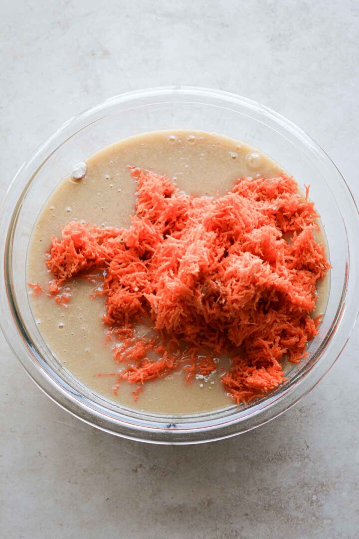 Step 3 for making carrot cake muffins - adding grated carrots.