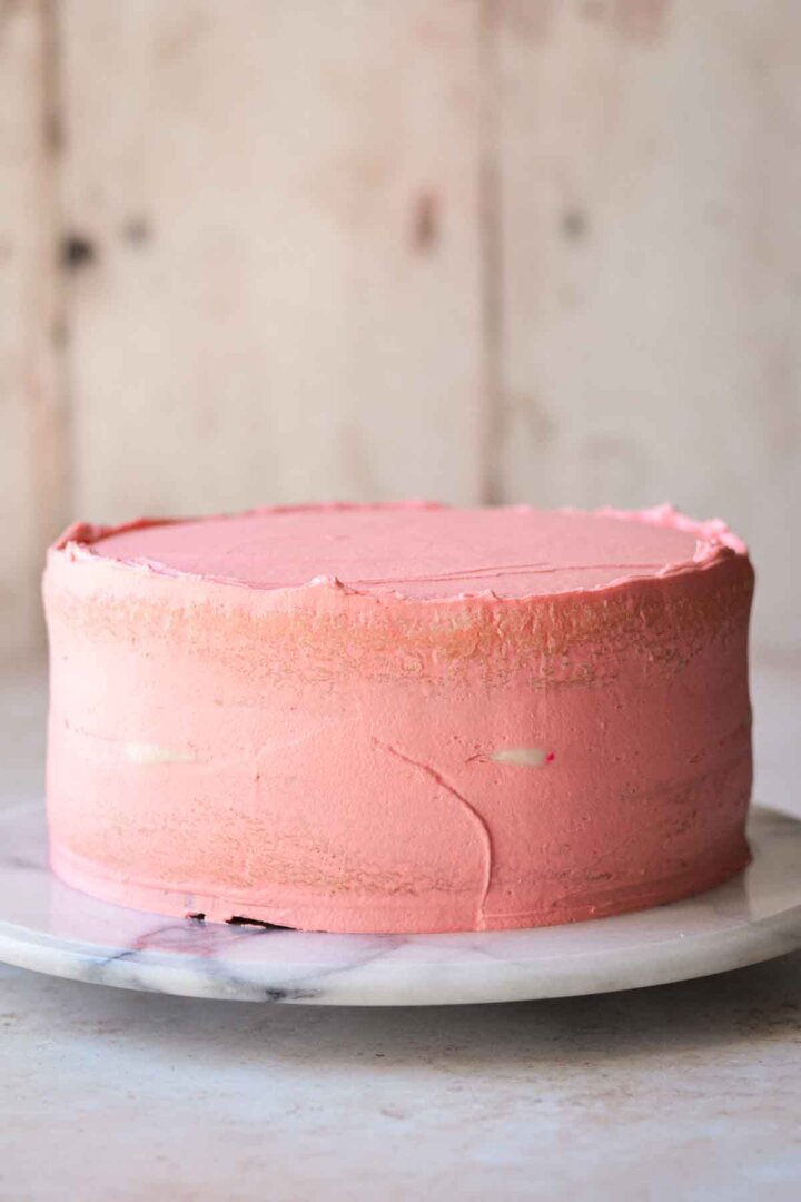Step 6 for assembling a sugar cookie sprinkle cake - frosted with crumb coat of buttercream.