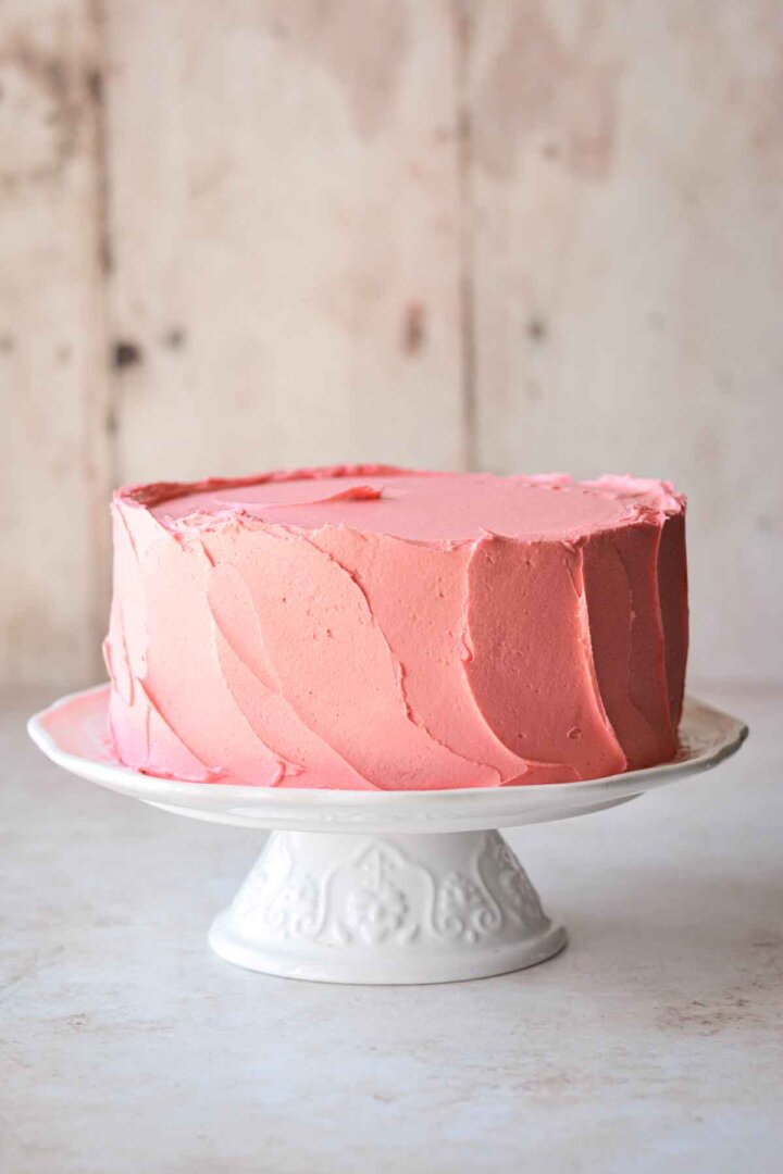 Step 7 for assembling a sugar cookie sprinkle cake - frosted with pink buttercream.