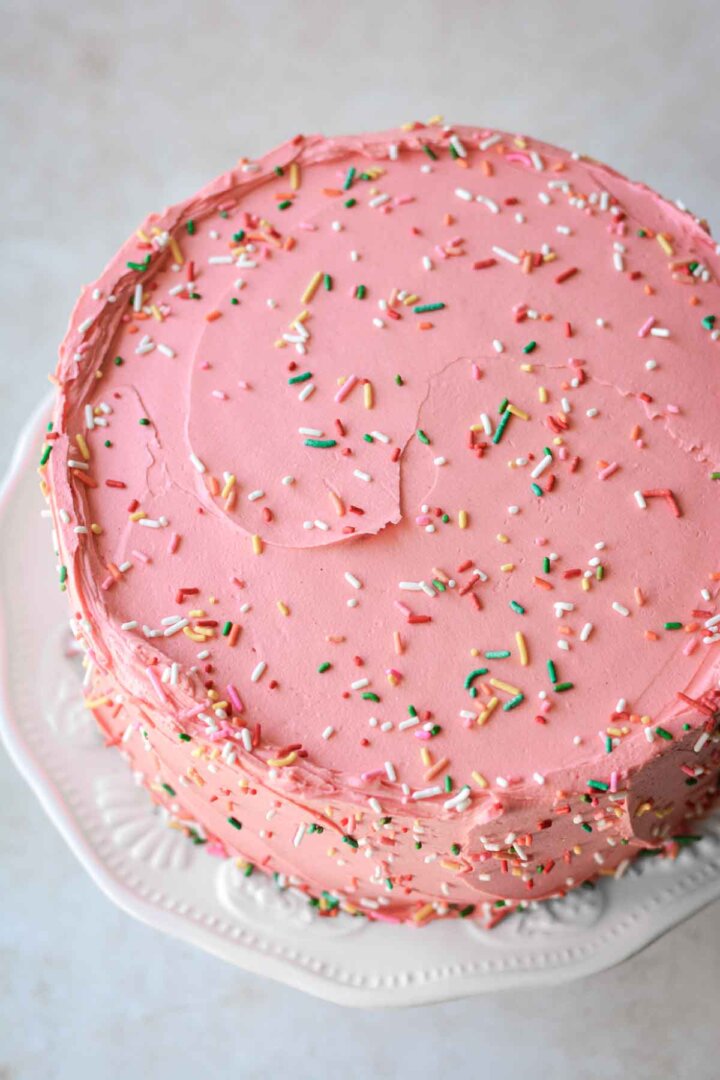 Sprinkles on a pink frosted cake.