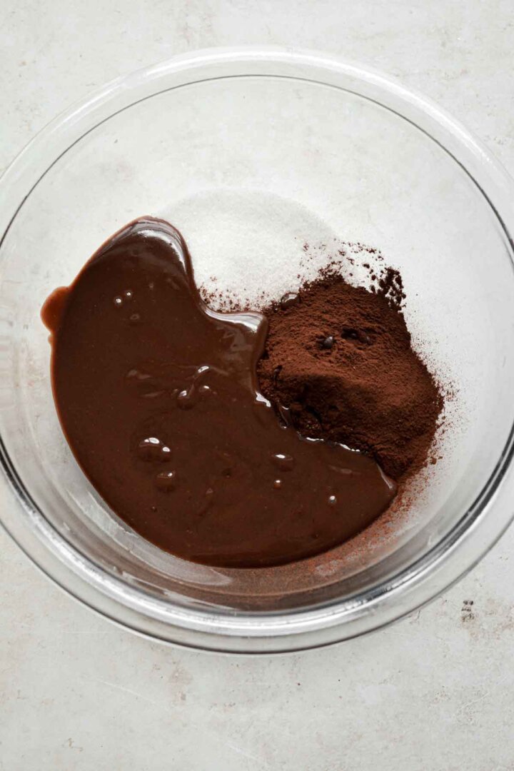 Step 3 for making brownie batter ice cream - stirring melted chocolate into sugar and cocoa powder.