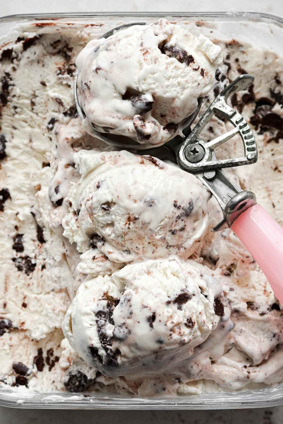 Scoops of brownie batter ice cream with a pink ice cream scoop.