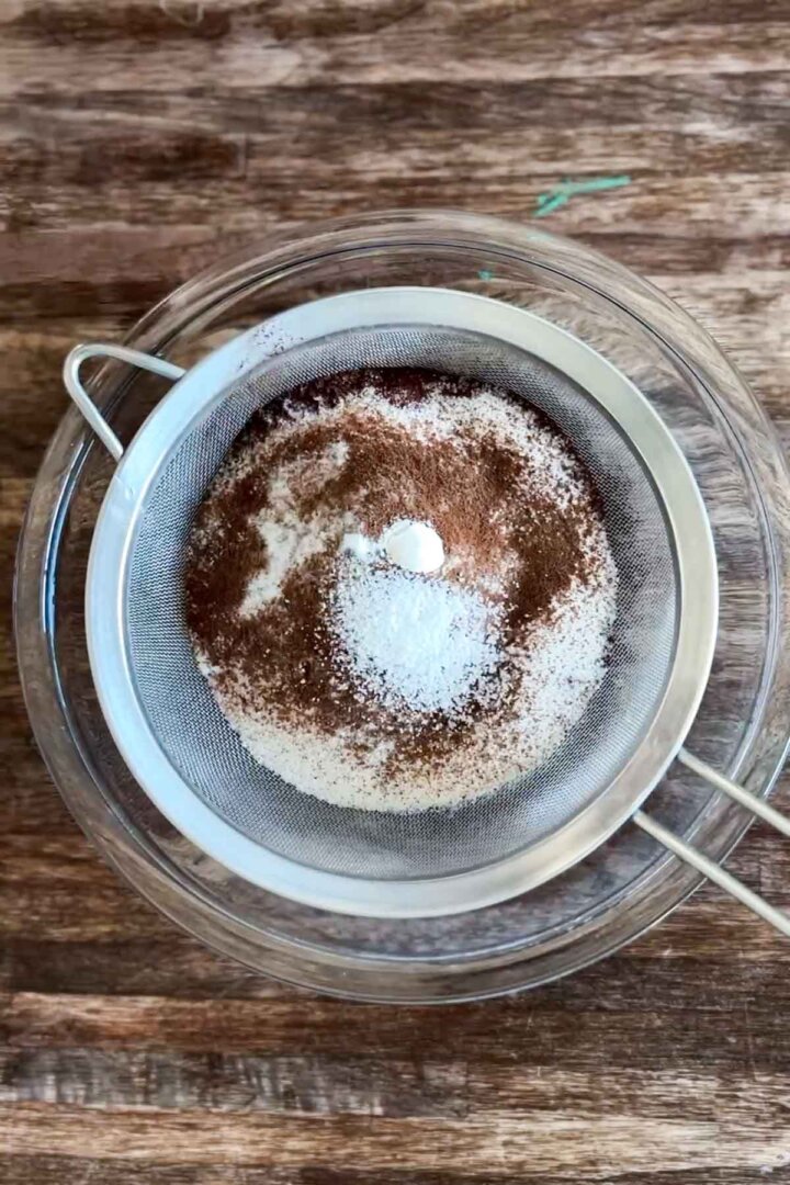 Step 1 for making gluten free chocolate cake batter - sifting dry ingredients.