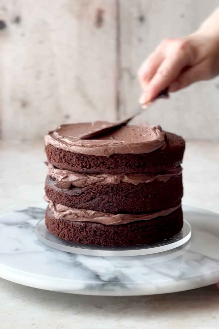 Frosting chocolate cake layers with chocolate buttercream.