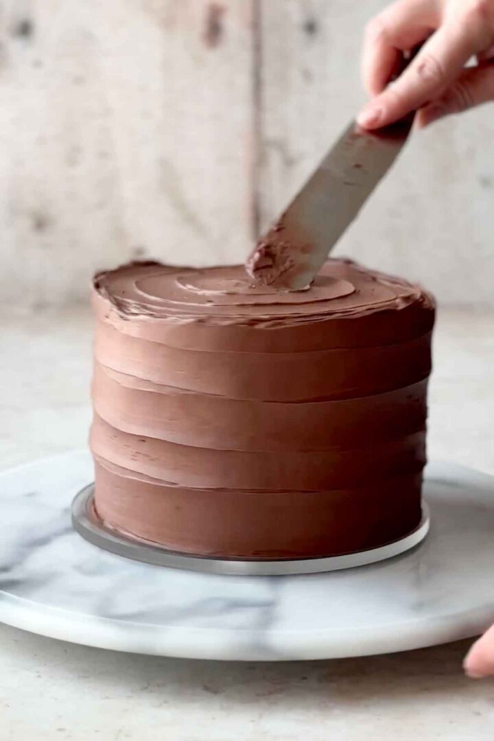 Frosting chocolate cake layers with chocolate buttercream.
