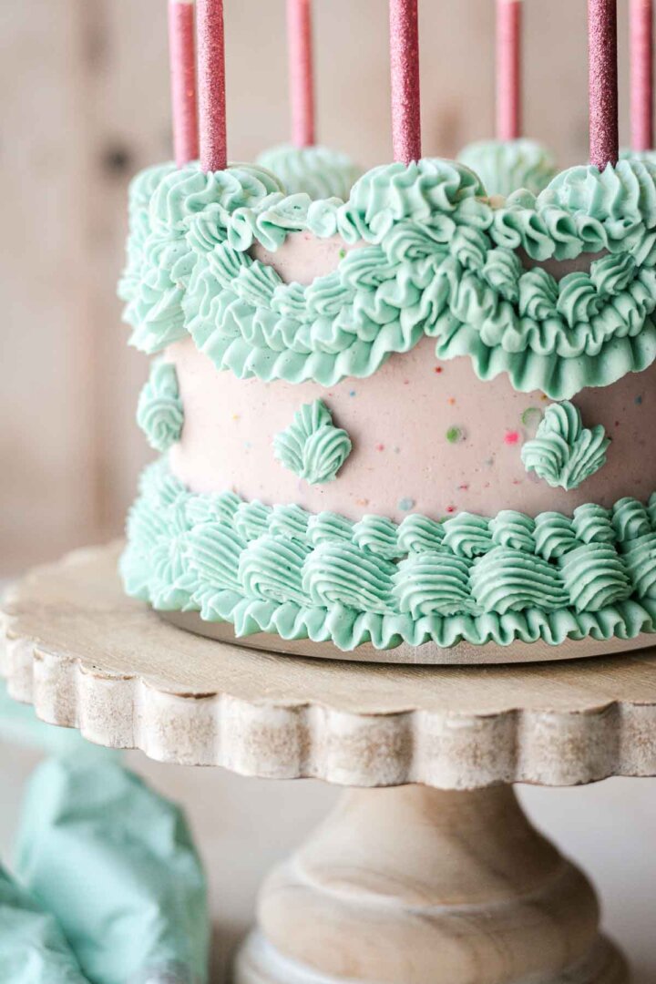 Pink and blue Lambeth cake with vintage ruffly piped buttercream and pink birthday candles.