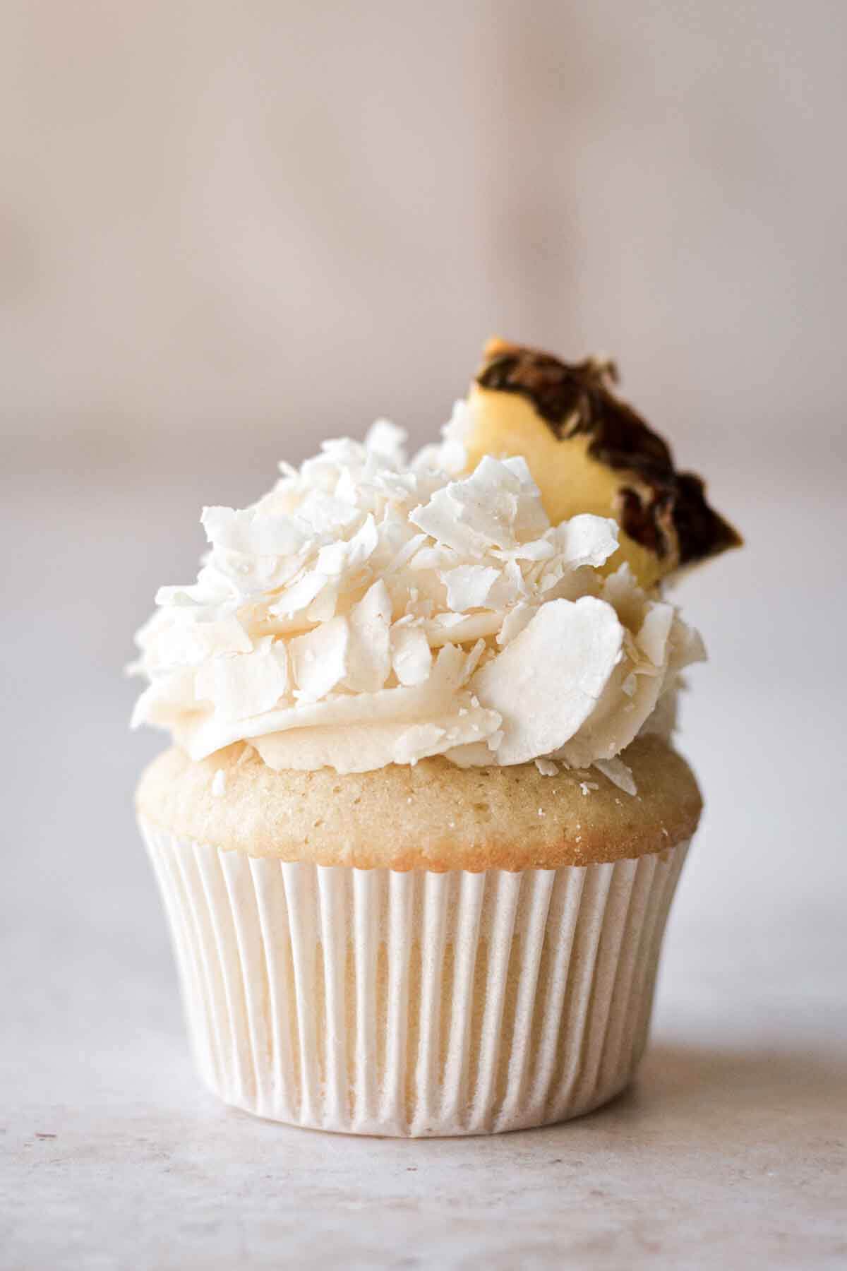 Pineapple coconut (pina colada) cupcake topped with a wedge of pineapple.