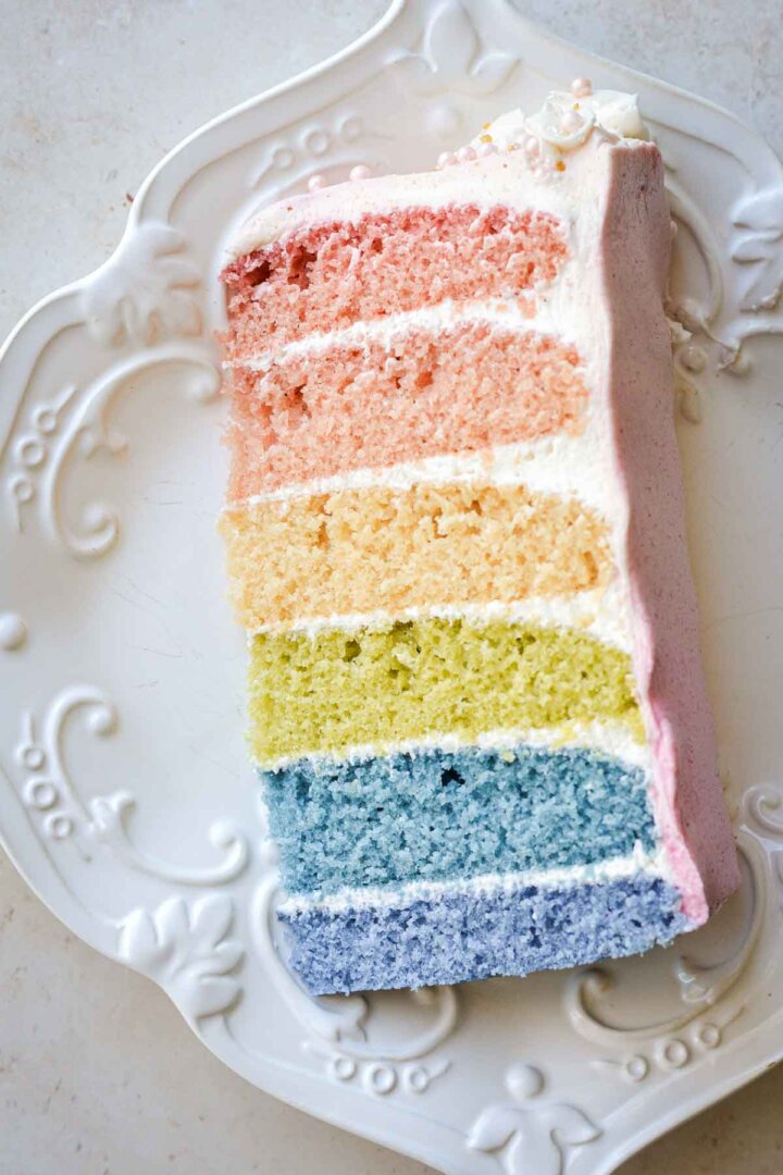 Slice of six-layer rainbow cake on a plate.
