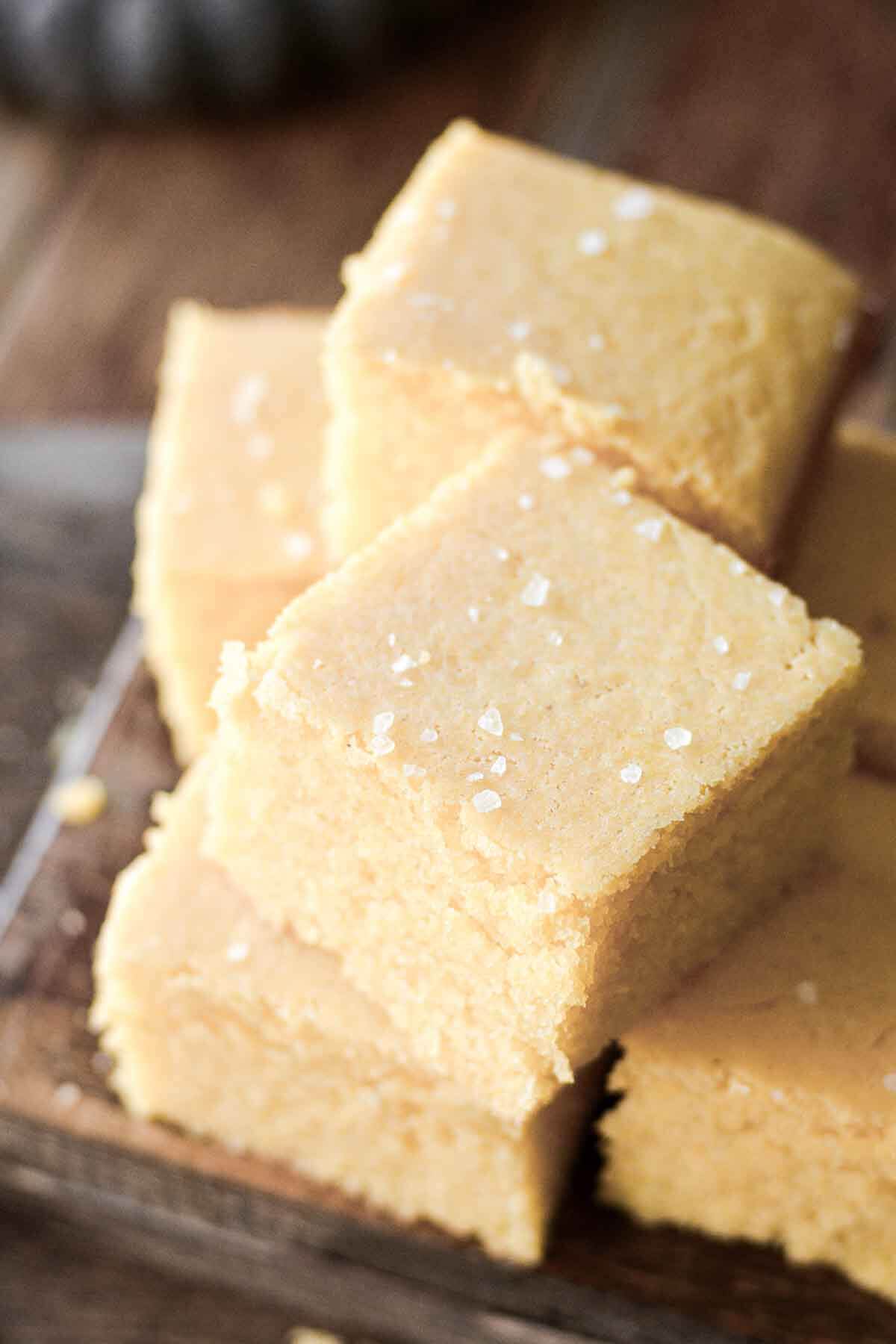 Squares of corn bread, stacked on a cutting board.