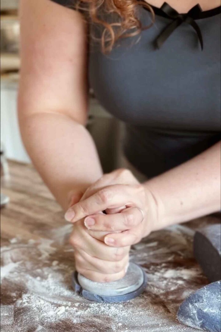 Pressing cookie dough with a cookie stamp.