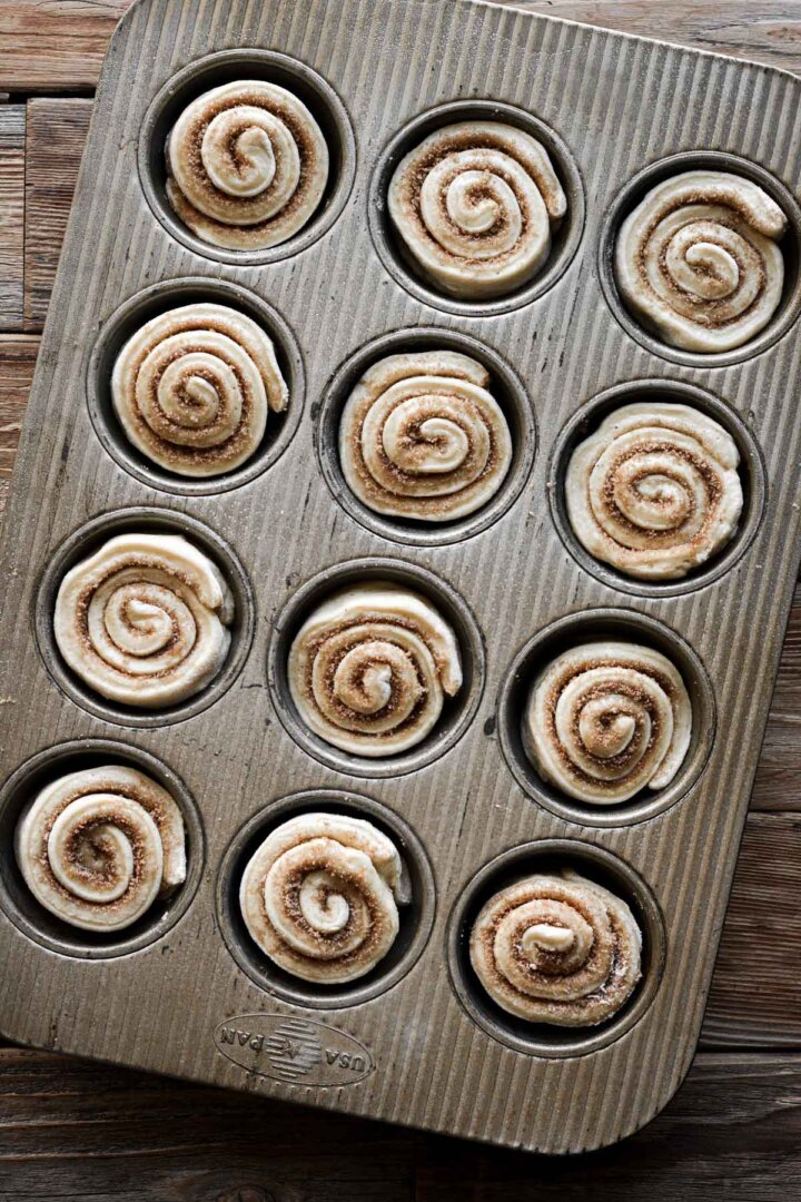 Cinnamon rolls rising in a muffin pan.