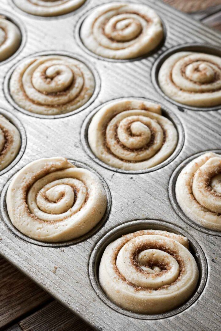 Cinnamon rolls rising in a muffin pan.