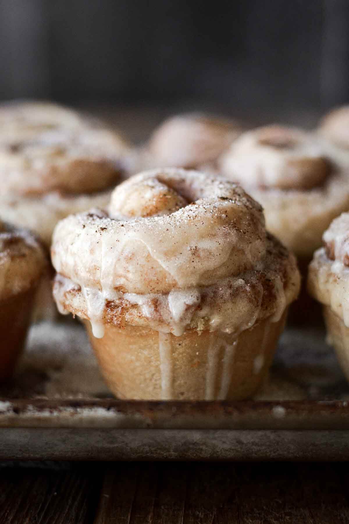 Orange icing drizzled over cinnamon rolls.