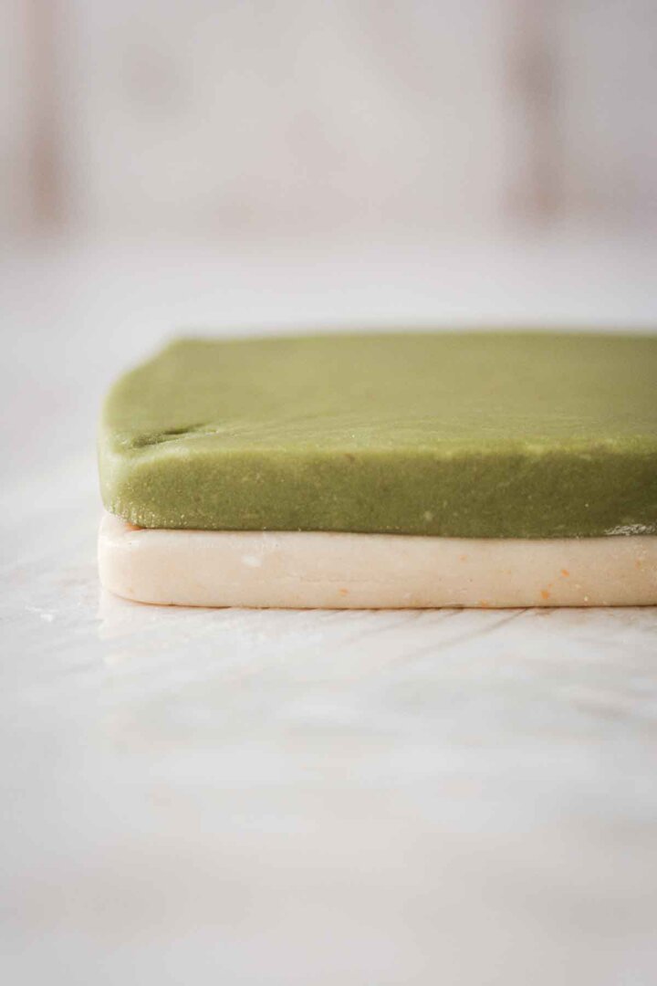 Step 1 for making green and white checkerboard cookies - stacking two squares of dough.