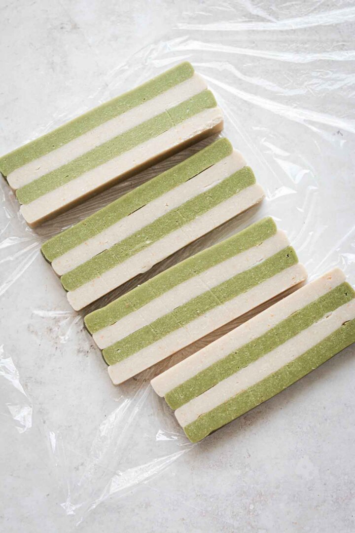 Step 4 for making green and white checkerboard cookies - cutting long slabs of striped dough.