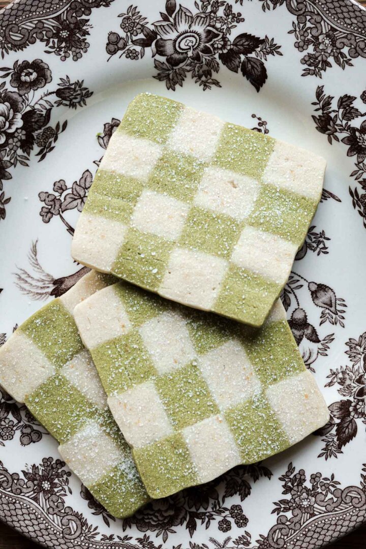 Green and white checkerboard cookies on a brown flowered plate.