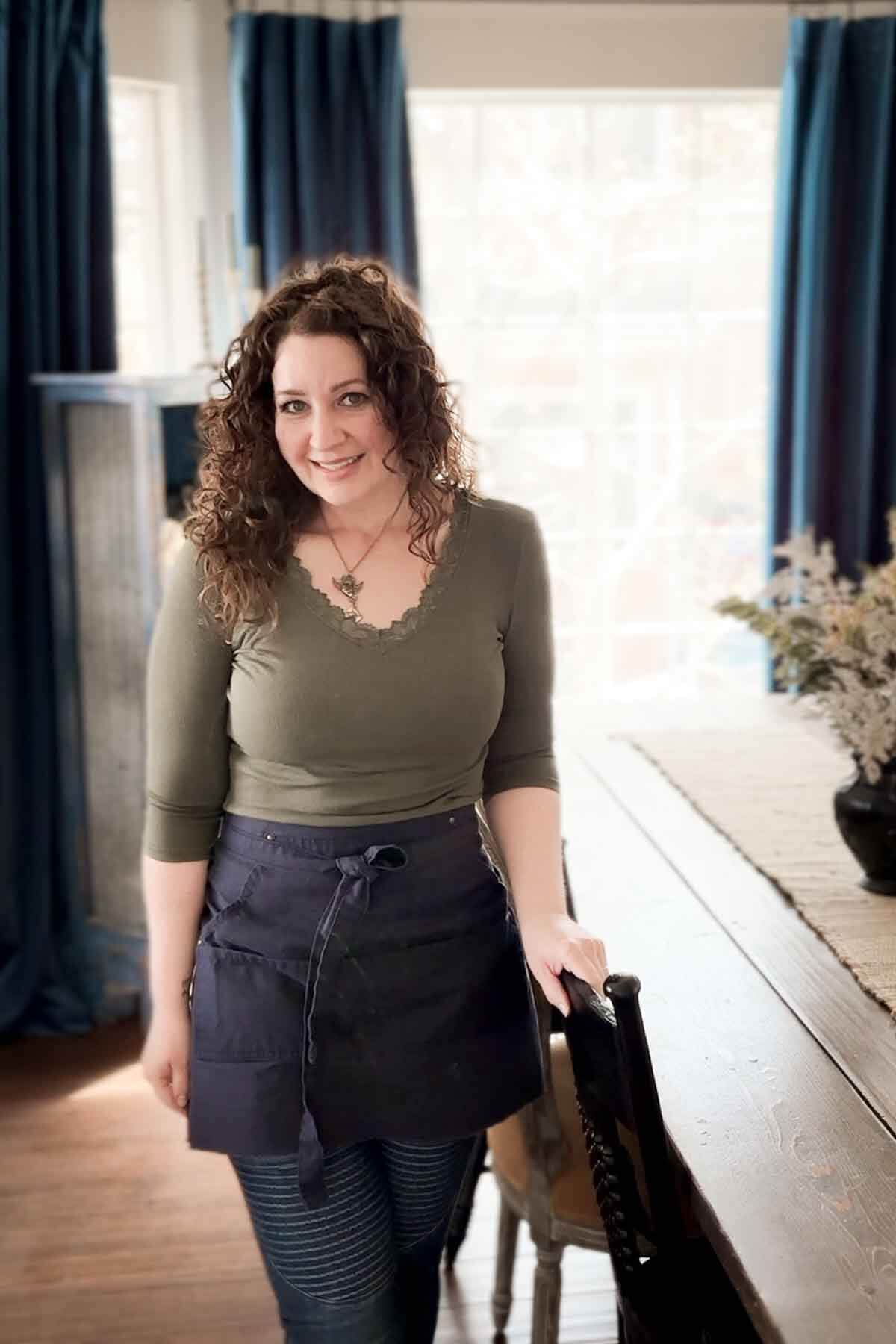 A woman standing beside a dining room table.