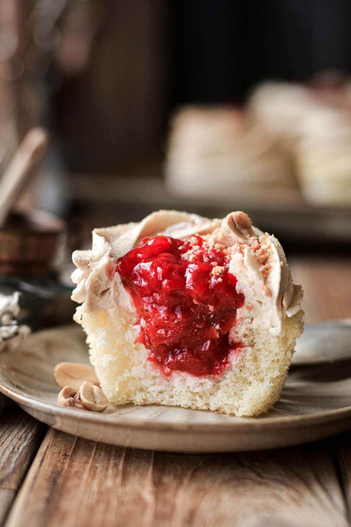 Peanut butter and jelly cupcake with a bite taken to show the strawberry filling.